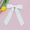 Dettaglio del fiocco in seta bianca con nastri lunghi su sfondo rosa pastello - Bianco