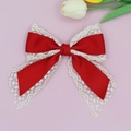 Close-up of elegant red bow hair clip with white lace trim on a soft pink floral background - Red