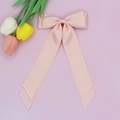 Gros plan sur l'élégante pince à cheveux en satin rose abricot avec de longs rubans - Rose chair