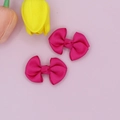 Detail of two fuchsia grosgrain ribbon bow hair clips on a soft pink floral background - Rose Red