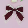 Detail of elegant wine red satin and lace bow hair clip with flowing ribbon tails - Burgundy