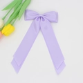 Gros plan d'un n\u00f3ud de cheveux en satin lavande avec de longs rubans sur fond blanc pur - Mauve Clair