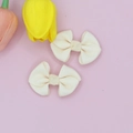 Close-up of cream-colored ribbed fabric bows with elegant knot detail on pink background - Off White