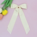 Détail d'un nœud papillon en satin crème avec de longs rubans sur fond rose doux - Beige