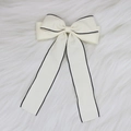 Detail van de gebroken witte haarclip met strik, zwarte rand en getextureerde jacquard stof - Beige