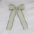 Detailed view of sage green jacquard bow hair clip with black satin piping on faux fur - Green