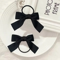 Elegante par de gomas para el pelo con lazo de satén negro sobre un plato decorativo - Negro