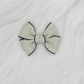 Détail du nœud papillon en jacquard vert clair avec bordure sur fond de fourrure blanche - Vert