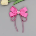 Détail d'un nœud papillon en ruban gros-grain rose avec un cœur en strass brillant - Rose foncé