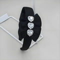 Dettaglio di strass a cuore su cerchietto in raso nero con grande fiocco elegante - Cuore
