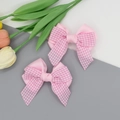 Vue détaillée de barrettes à nœuds à carreaux roses montrant la texture du tissu - Rose