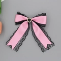Close-up of pink satin bow hair clip with black lace edges and heart rhinestone detail - Pink