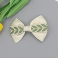 Dettaglio del fiocco in raso beige con ricamo a foglie verdi e consistenza del nastro lucido - Bianco Sporco (Con Foglia Verde)
