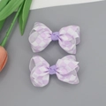 Dettaglio di due fermagli per capelli con fiocchi a quadretti viola e bianchi per bambine - Viola