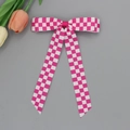 Détail d'une pince à cheveux à carreaux roses et blancs avec de longs rubans élégants - Rose rouge
