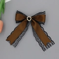 Detailed macro view of coffee brown satin bow clip with black lace and heart gemstone - Coffee