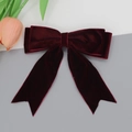 Detail shot of deep wine red velvet oversized bow hair clip on minimalist background - Burgundy