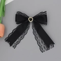 Detalle de una pinza para el pelo con lazo de encaje negro y piedra en forma de corazón - Negro