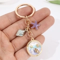 Llavero de caracol marino dorado con estrella de mar púrpura y colgantes de playa azul - Morado