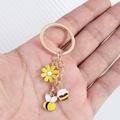Detail of metal bee keychain with yellow enamel flower and honey pot charm on hand - Bee Style (蜜蜂)