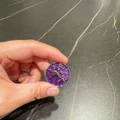 Sparkling purple round pet tag with silver paw prints held in hand for size comparison - Purple