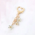 Golden heart-shaped keychain featuring delicate white and green enamel flower pendants - Blue and White Lily