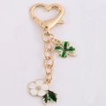 Portachiavi con chiusura a cuore dorata, quadrifoglio verde e ciondolo a forma di fiore bianco - Camelia