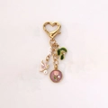 Llavero de corazón dorado con mariposa rosa y colgantes florales de esmalte en fondo blanco - Tulipán de Placa Redonda