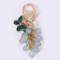 Druiventros sleutelhanger met lichtblauwe kralen en groene emaille vlinderhanger - Blauw