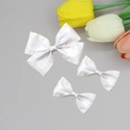 Detail of white pleated satin bow hair clips with delicate textured edges and soft silk luster - White