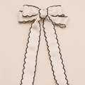 Detail van de crèmekleurige haarstrik met zwarte golfkanten en lange satijnen linten - Beige Met Zwarte Rand