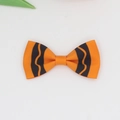 Close-up of orange grosgrain ribbon bow hair clip with black wavy pattern for girls - Orange
