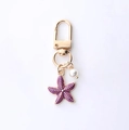 Golden keychain featuring a purple enamel starfish and a white pearl charm for bags - Purple Starfish and Artificial Pearl Style (Starfish Butterfly)