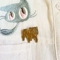 Gros plan détaillé d'une broche bouledogue en émail marron sur une poche de chemise - Style Shar Pei