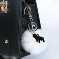 Détail d'un porte-clés pompon blanc avec breloque bouledogue noir sur un sac à main noir - Bouledogue Noir