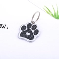 Macro shot of silver paw-shaped pet ID tag with black glitter inlay and heart detail - Black