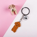 Close-up of orange poodle keychain with black and white paw print charm on metal ring - Large Brown Dog With Paw Tag