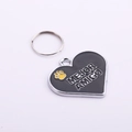 Detail of heart-shaped metal pet ID tag with black enamel and yellow paw print design - Black Heart