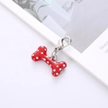 Dettaglio del ciondolo a forma di osso rosso con pois bianchi e moschettone argento - Rosso