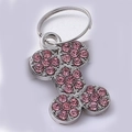 Dettaglio macro della medaglietta a forma di osso con strass rosa e finitura argento - Osso Rosa