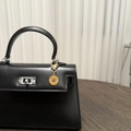 Dettaglio del ciondolo a girasole dorato su una mini borsa in pelle nera di lusso - Margherita Gialla