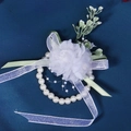 Detail of a white tulle wedding wrist corsage with artificial pearls and green leaf accents - 2-Flower Wristlet