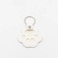 Close-up of white leather cat paw keychain with silver metal ring and fine stitching - White