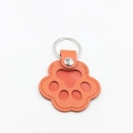 Detalle de llavero de cuero con forma de pata de gato, textura naranja y anillo de metal - Naranja