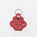 Detalle de llavero de pata de gato en cuero rojo con anillo de metal y ventana clara - Rojo