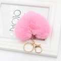 Close-up of pink heart-shaped faux fur keychain with golden chain on white frame - Pink