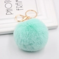 Macro shot of fluffy mint green faux fur pom pom keychain with gold metal hardware - Light Green