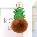 Gros plan d'un porte-clés ananas en fourrure synthétique marron et feuilles pailletées - Brun