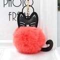 Detailansicht des korallenrosa Pelz-Pompons mit schwarzem Leder-Katzen-Design und Goldring - Orangerot