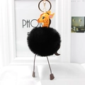 Detail of a fluffy giraffe plush keychain with black faux fur ball and gold metal ring - Black